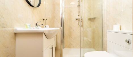 A modern bathroom with a glass-enclosed shower, a white sink, and a toilet.