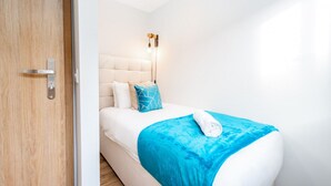 Un dormitorio moderno con cama, lámpara de noche y puerta de madera.