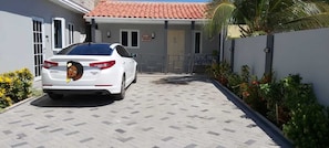 A white car parked in a driveway with a tiled roof and a gated entrance.