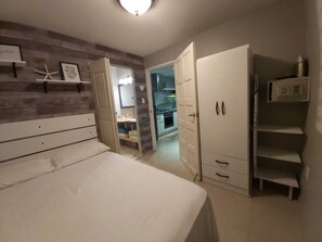 A bedroom with a bed, a wardrobe, and a bathroom visible through an open door.
