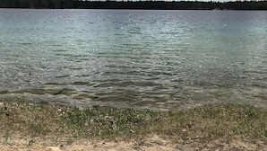 Une plage de sable où l’on peut voir des empreintes de pas qui mènent à un lac.