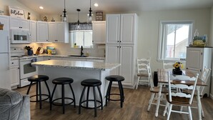 Une cuisine moderne avec des meubles blancs, un plan de travail en granit et un îlot central doté de tabourets de bar.
