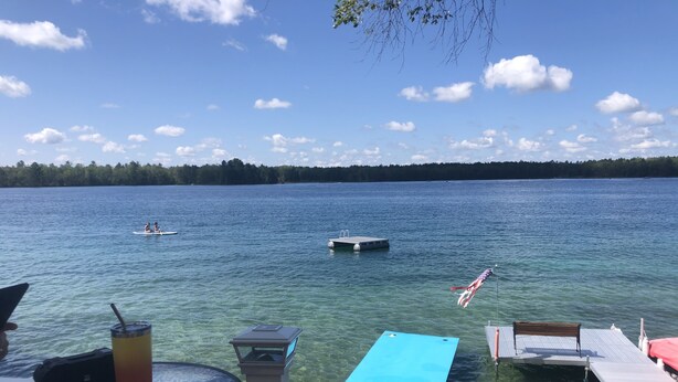 On voit clairement un lac avec un quai, une table avec une boisson et un drapeau.