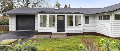 A single-story house with a black front door, white siding, and a garage.