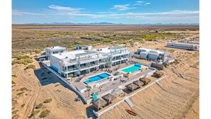 A modern hotel with multiple buildings, a swimming pool, and a desert landscape in the background.