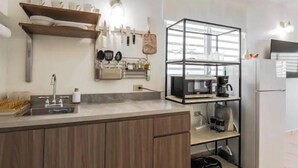 A modern kitchen with a central island, built-in shelves, and a refrigerator. - City Park View - Cozy Studio (Guaynabo)