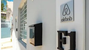 A white wall with the Airbnb logo and the letters "F1" mounted on it. - City Park View - Cozy Studio (Guaynabo)