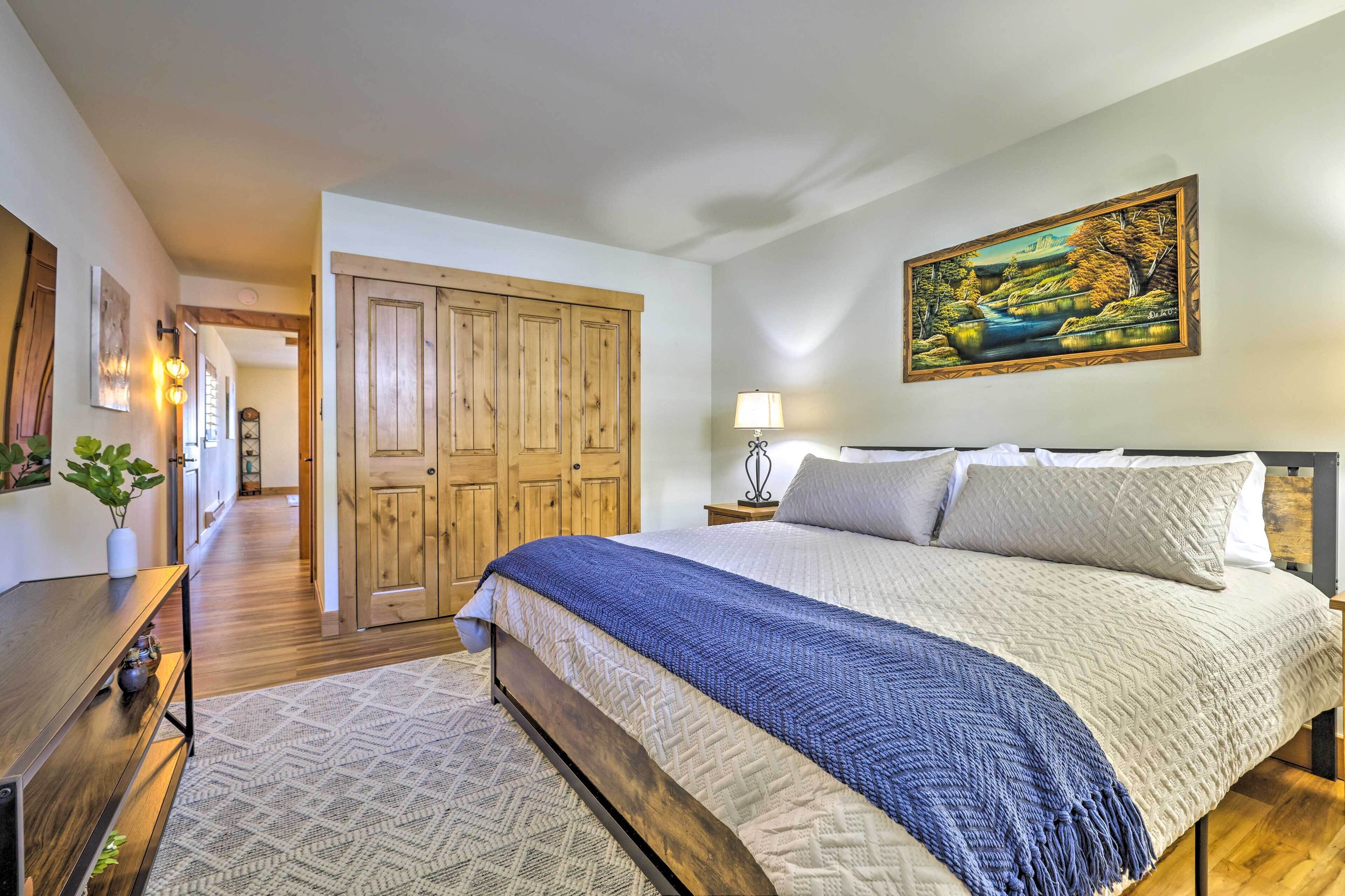 A bedroom with a large bed, wooden wardrobe, and a painting on the wall.