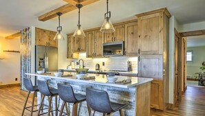 Une cuisine moderne avec des meubles en bois, un îlot central doté de tabourets de bar et un éclairage suspendu.