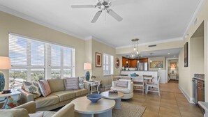 A spacious living room with a sofa, coffee table, and a dining area with a kitchen in the background. - MVG 1416 Ocean View Penthouse (North Myrtle Beach)