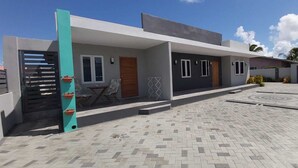 Et moderne hus med en belagt indkørsel, en overdækket veranda og et lille udendørs siddeområde.