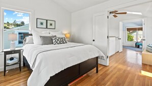 Un dormitorio con cama, mesita de noche, lámpara y vistas al exterior.