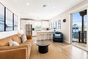 A modern kitchen with white cabinets, a stainless steel refrigerator, and a large window.