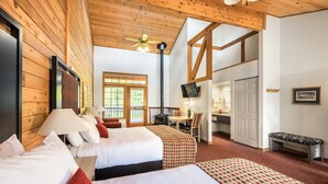 A hotel room with two beds, a wooden ceiling, a television, a desk, and a fireplace. - Kenai Princess Wilderness Lodge (Cooper Landing)