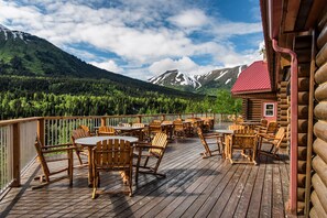 A wooden deck with outdoor seating and a mountain view. - Kenai Princess Wilderness Lodge (Cooper Landing)