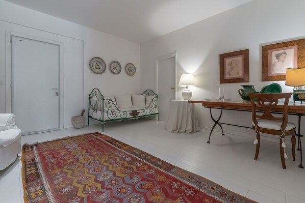 Una habitación con cama, una mesa con sillas, un tapete estampado y adornos en la pared.