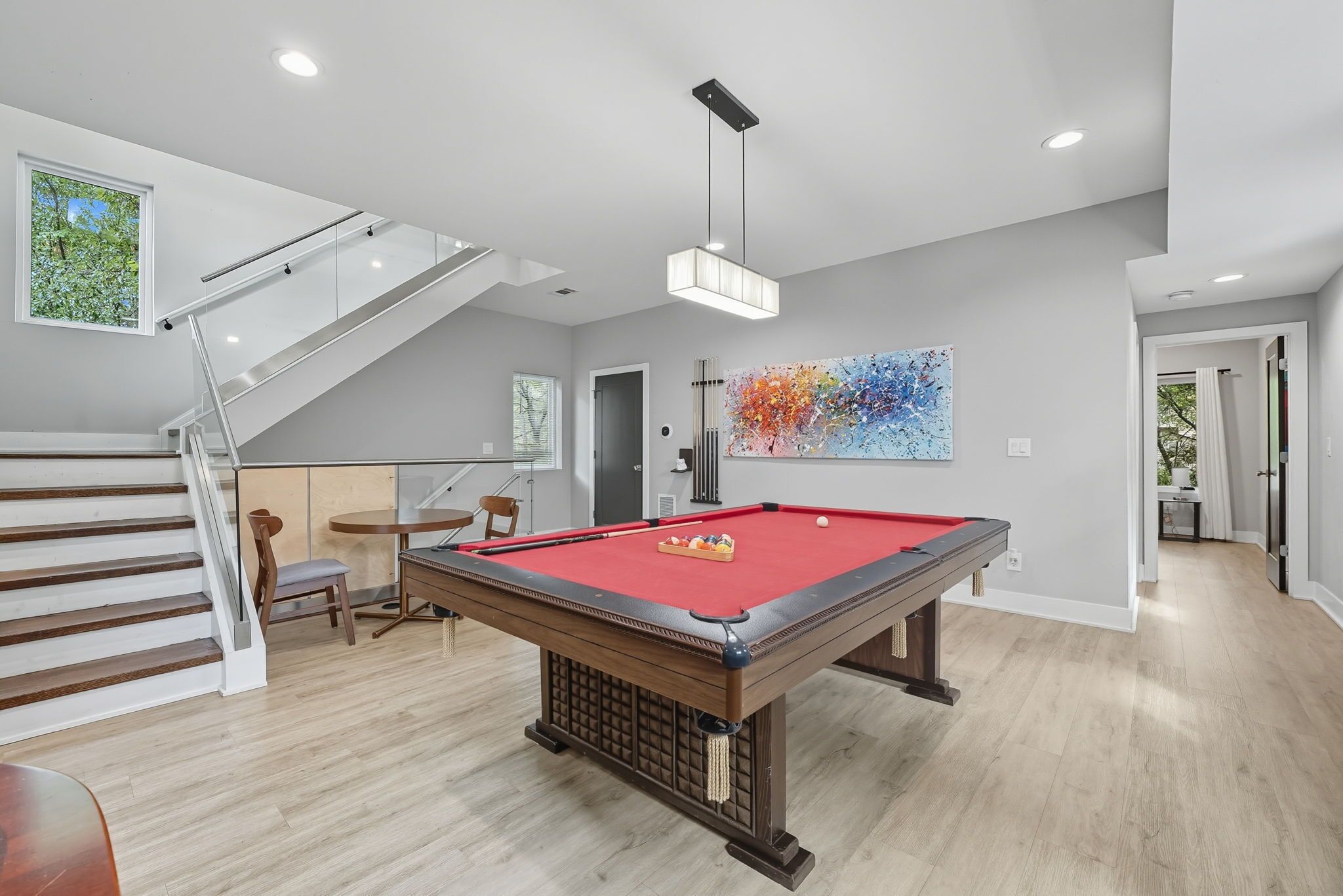 Un salon moderne avec une table de billard, un escalier et un coin repas.