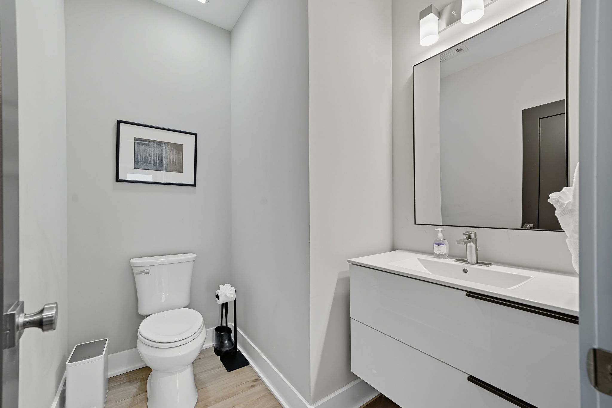 A modern bathroom with a toilet, sink, and mirror.