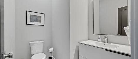 A modern bathroom with a toilet, sink, and mirror.