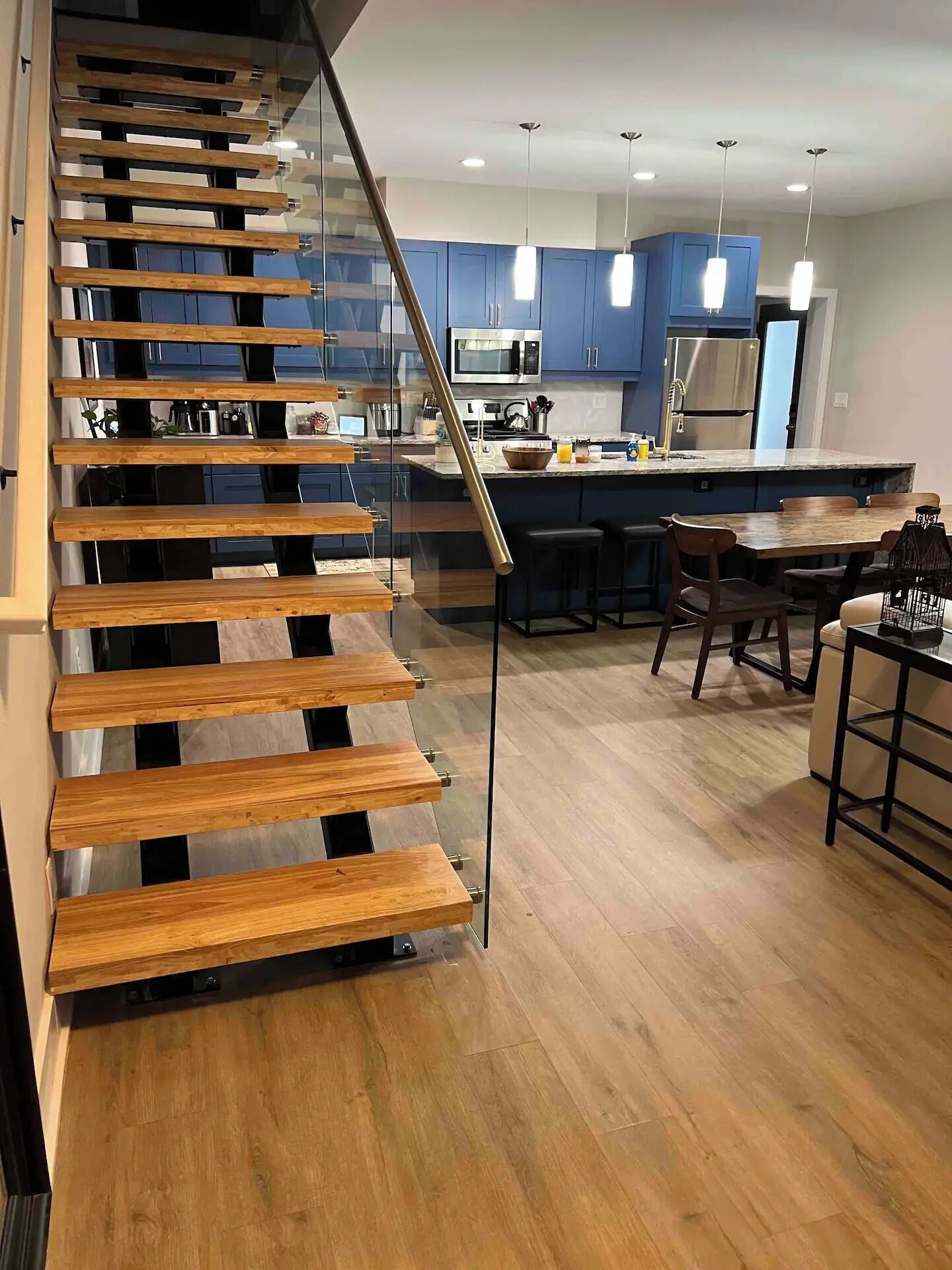 Eine moderne Küche mit blauen Schränken, einem Edelstahlkühlschrank und einer Holztreppe.