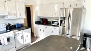 Una cocina moderna con armarios blancos, electrodomésticos de acero inoxidable y una isla grande.