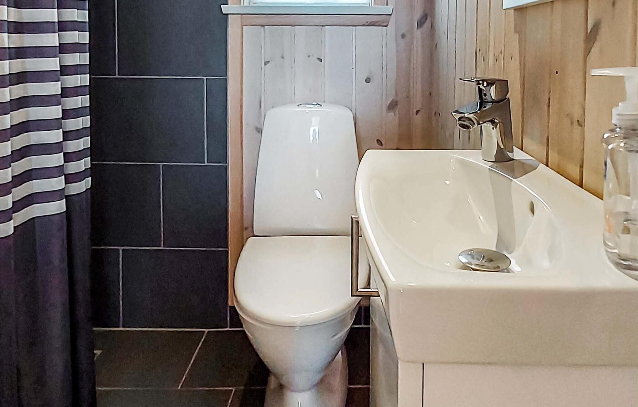A bathroom with a toilet, a sink, and a shower area.