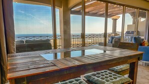 Una barra de madera con asientos acolchados y amplias ventanas que dan a la playa.