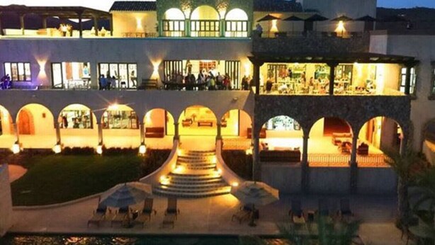 Un hotel con un patio central, varios balcones y una zona de piscina.
