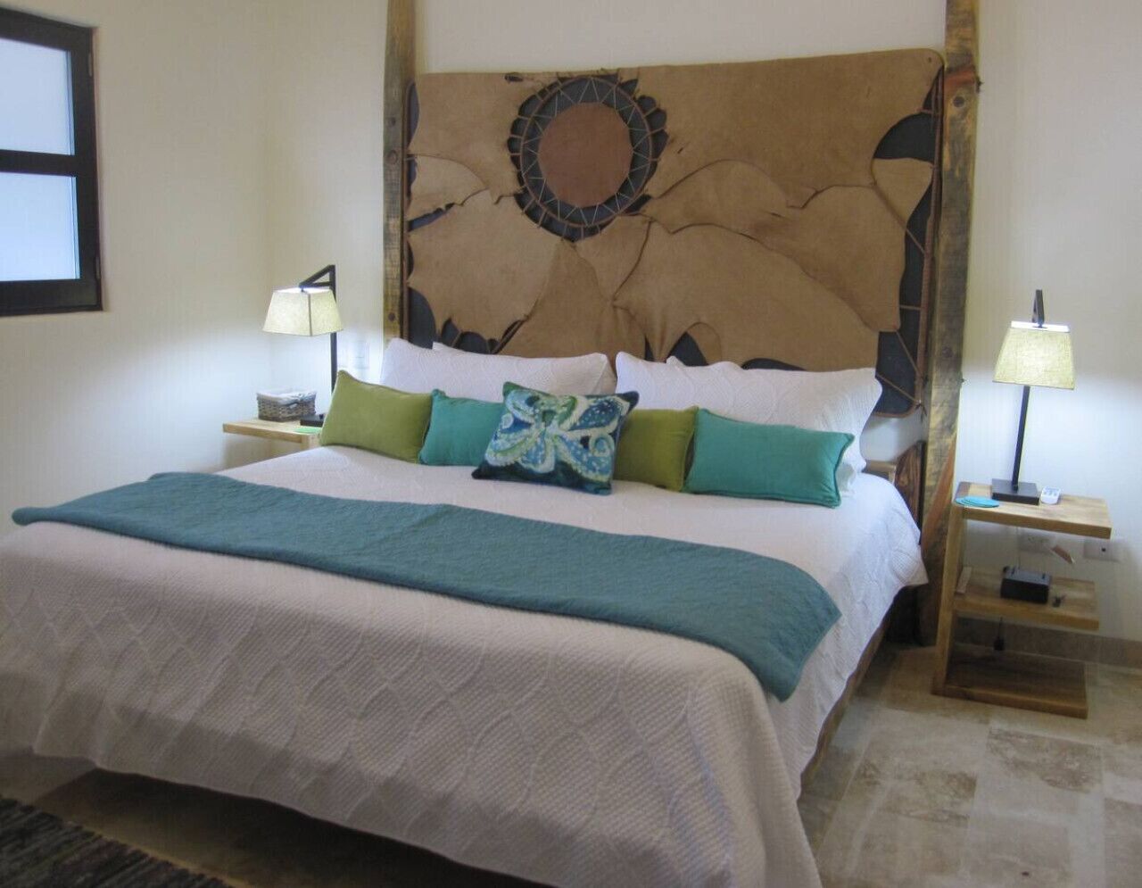 A bed with a decorative headboard, two bedside tables with lamps, and a patterned bedspread.