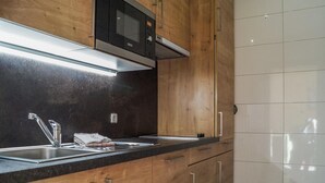 Eine Küche mit Holzausstattung, einem Edelstahlspülbecken, einer Mikrowelle und einer modernen Leuchte über der Arbeitsfläche.