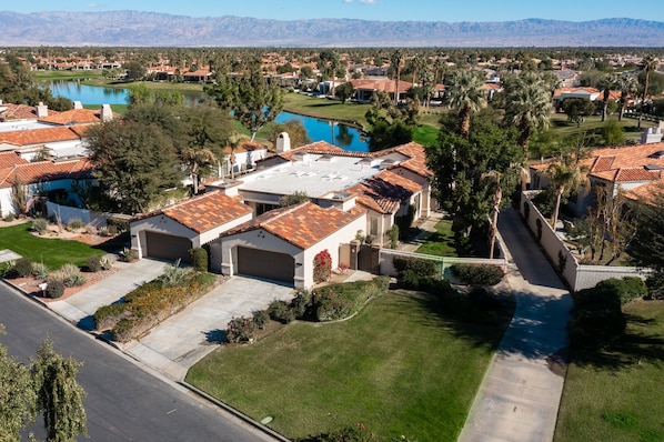 Un barrio residencial con casas de tejados rojos, una piscina y un campo de golf al fondo.