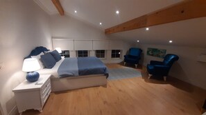 Une chambre à coucher avec un lit, une table de chevet, une lampe et deux chaises bleues.