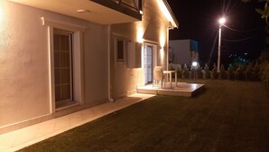Una casa moderna con un área de estar exterior techada y una entrada bien iluminada.