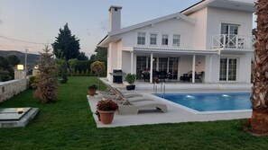 Une maison moderne dotée d’une piscine, d’un espace extérieur aménagé et d’un jardin bien entretenu.