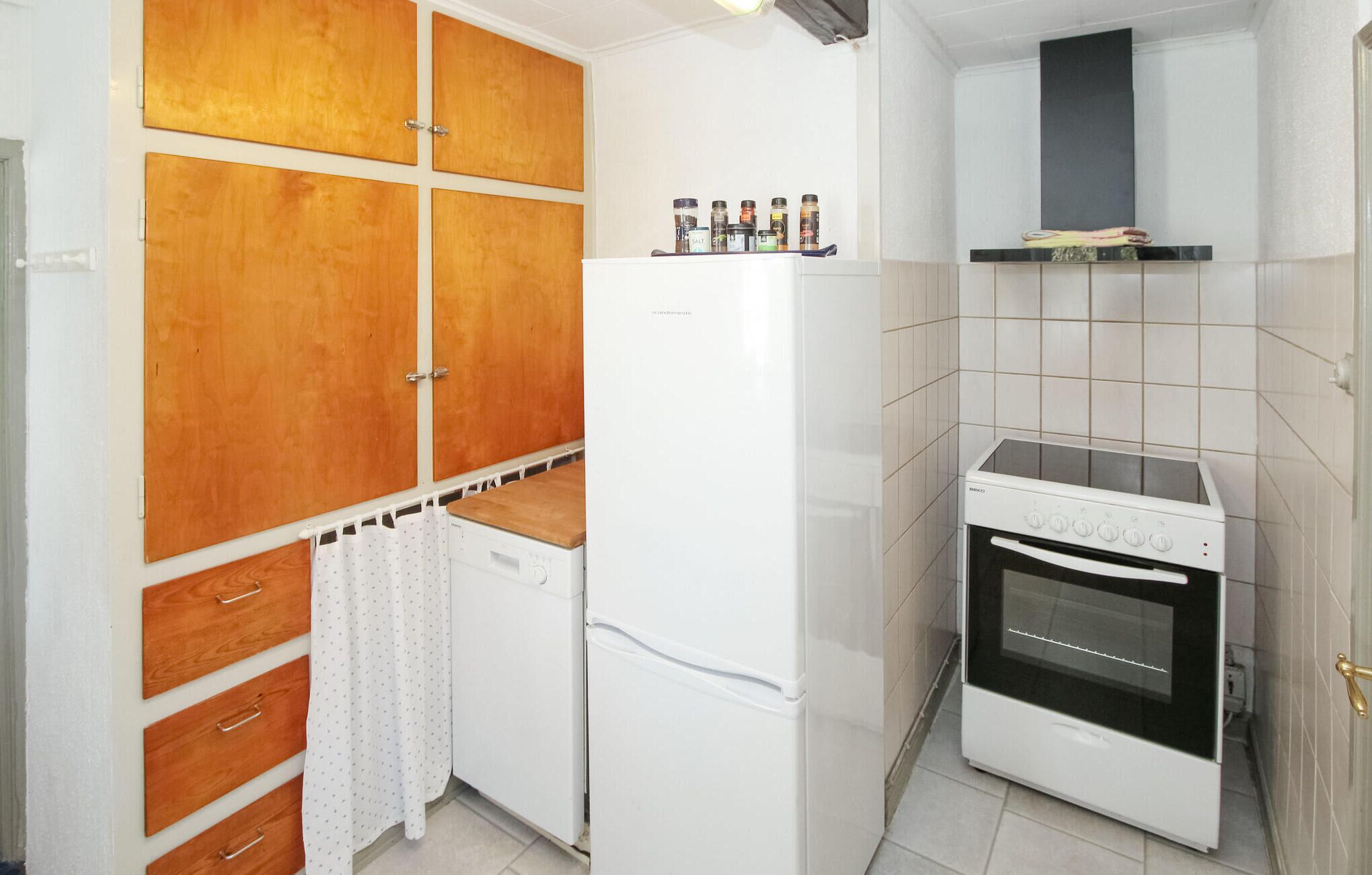 Una cucina compatta con un frigorifero bianco, un fornello e mobili in legno.