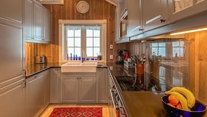Een kleine keuken met houten wanden, een inbouwoven en een raam met zonwering.