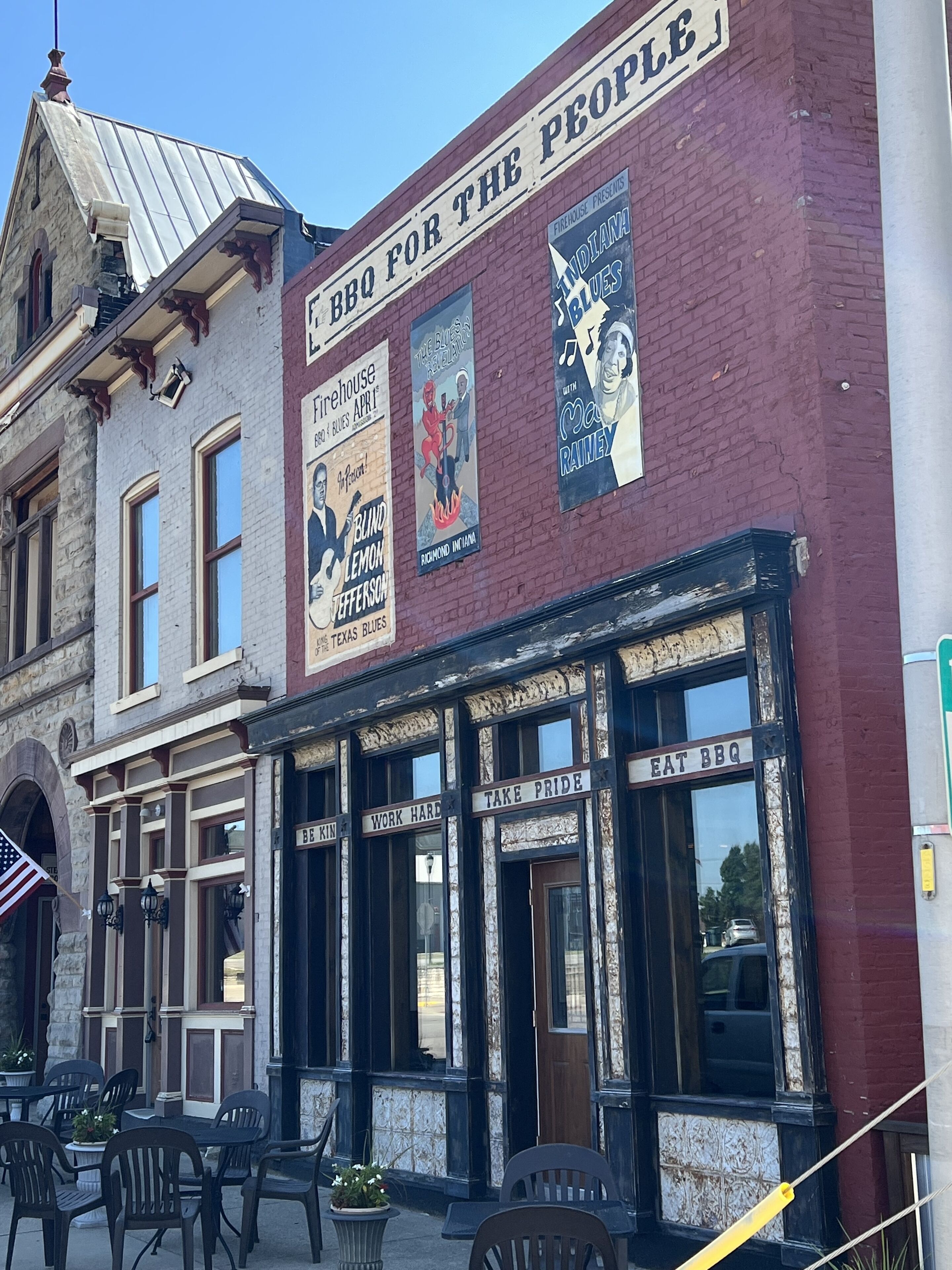 A building with a sign that reads "BBQ FOR THE PEOPLE" and several posters advertising events.