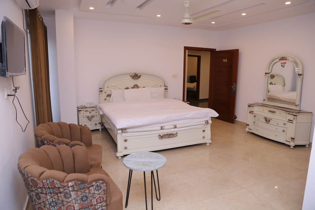 Une chambre à coucher avec un lit, une commode, une chaise et une petite table.