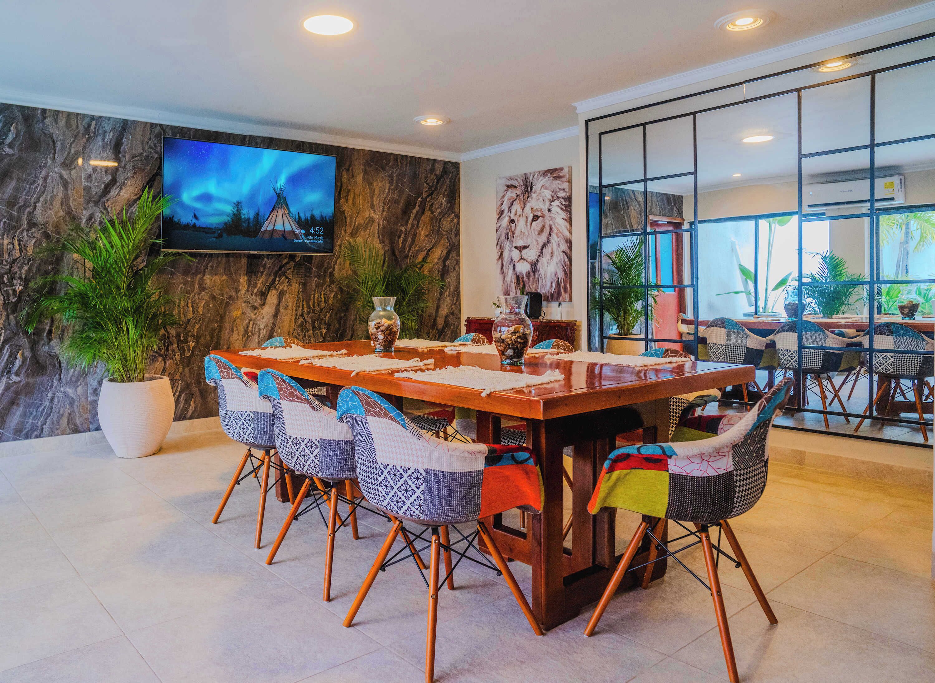 A dining area with a wooden table, chairs, a TV, and a large window.