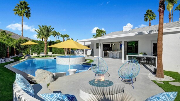 Un área de piscina moderna al aire libre, con un jacuzzi circular, sillones de descanso y una zona de bar.