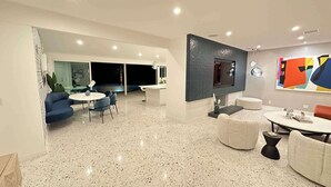 Una sala de estar moderna con comedor, chimenea y un cuadro abstracto grande en la pared.