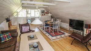Ett mysigt vardagsrum i loftstil med en matplats, en tv och en öppen spis.