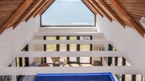 A room with a sloped ceiling and a large window overlooking the sea. - Gorgeous home in Samsø with sauna (Samsø)