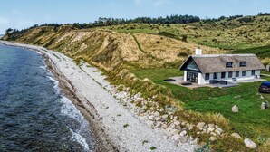 A coastal house with a thatched roof, a paved driveway, and a view of the sea. - Gorgeous home in Samsø with sauna (Samsø)