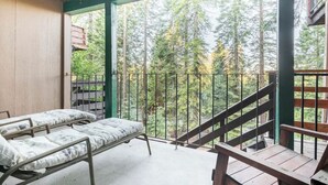 Una cabaña con dos camas de metal y un balcón con vistas a un bosque.