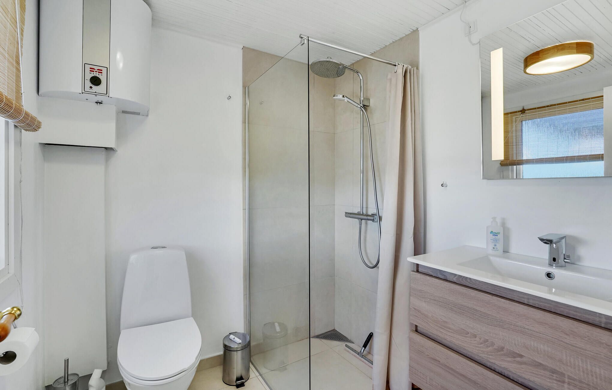 A modern bathroom with a glass-enclosed shower, a toilet, a sink with a wooden vanity, and a mirror with a wooden frame.