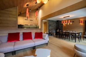 A modern living room with a sofa, red cushions, and a dining area with wooden furniture. - Chantemerle 19 prestige apartment ski-in / ski-out (Les Allues)