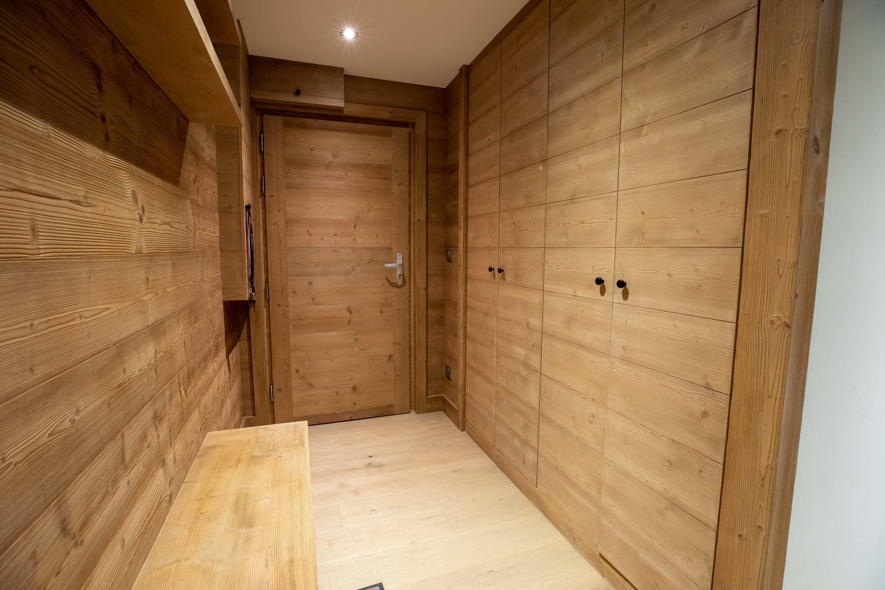 A narrow hallway with wooden walls and a wooden bench.