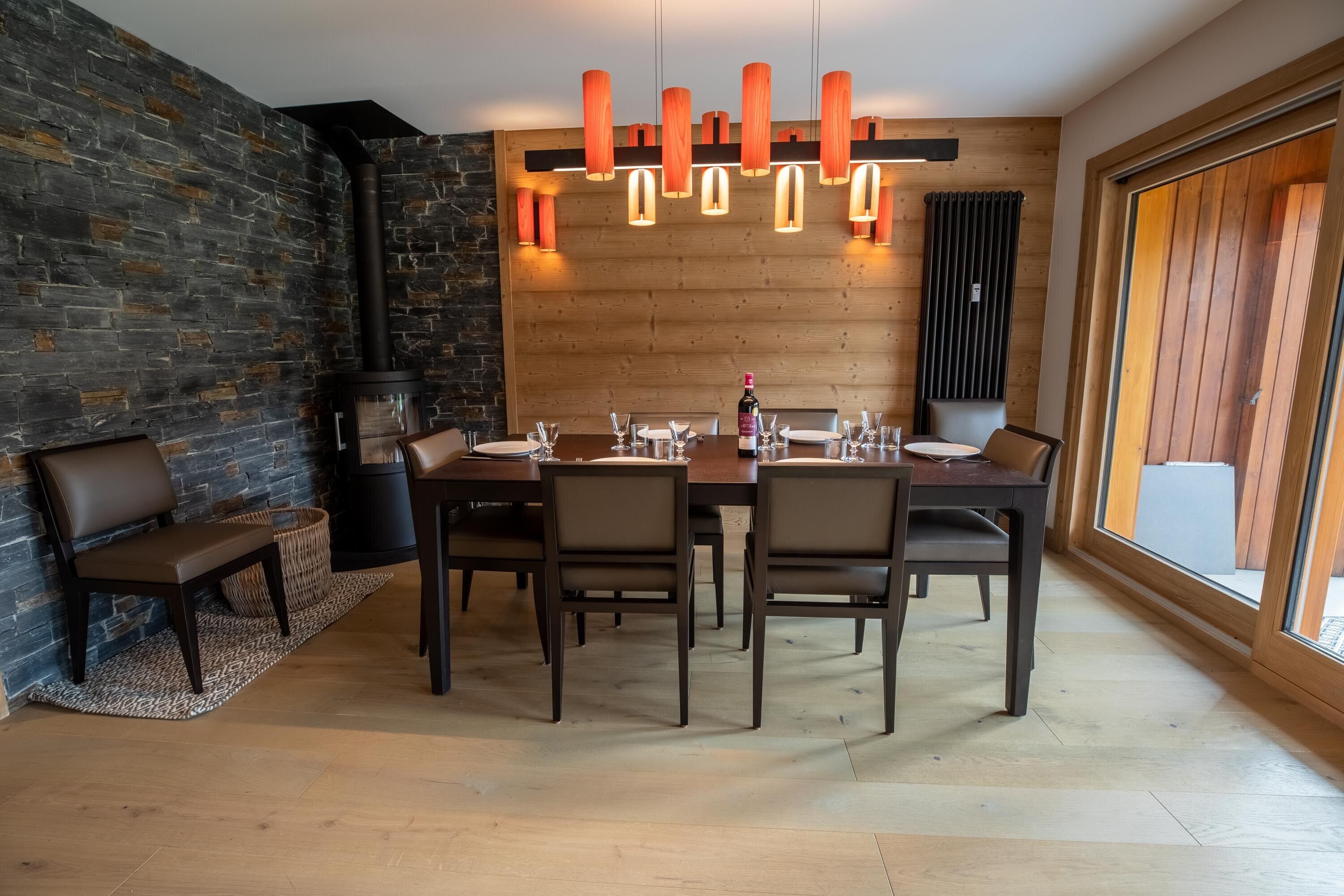 Un espace repas moderne avec un mur en pierre, un lambris en bois et une grande fenêtre.
