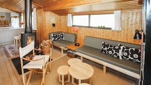 A cozy cabin interior with a wooden interior, a sofa, a bench, a table, and a fireplace. - Stunning home in Samsø with WiFi (Samsø)